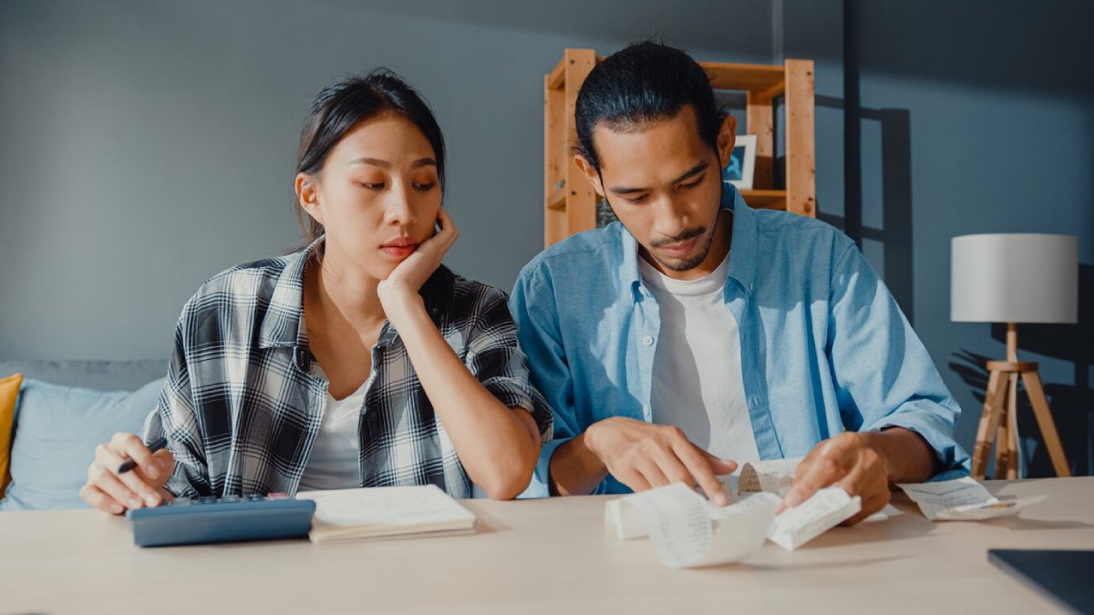 A man and woman review documents together at a table, looking concerned and focused.