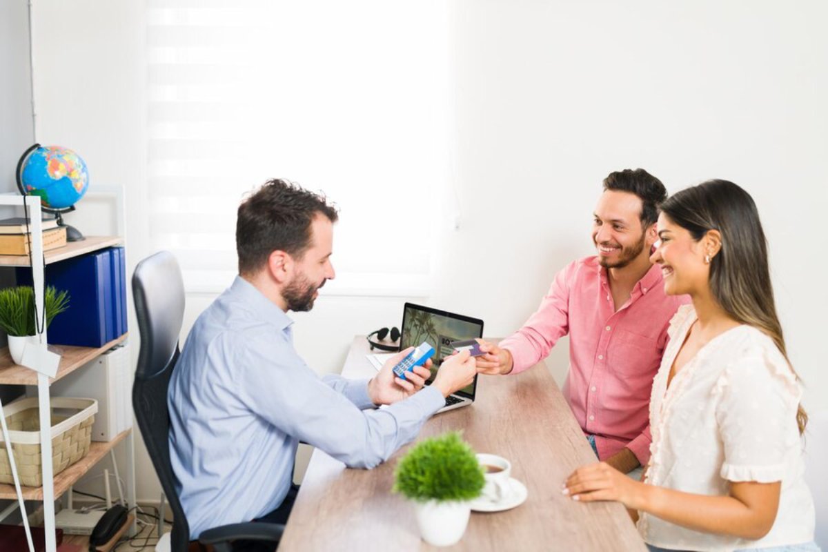 A financial advisor discussing options with a smiling couple in an office environment.