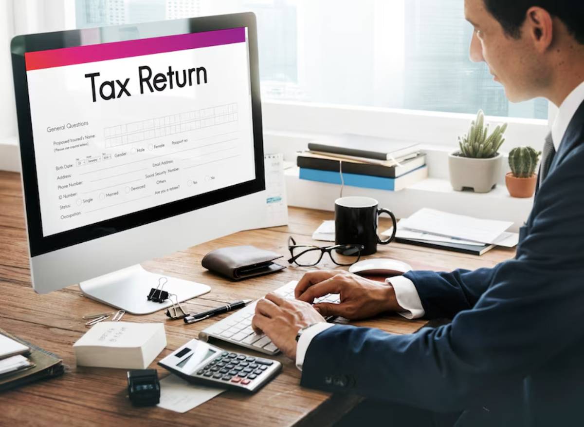 Man in business suit working on a tax return on a computer in a modern office setting.