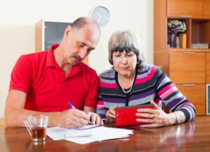 Mature couple reviewing documents together at a kitchen table.