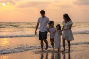 A family of four hiking on a coastal trail with cliffs and ocean in the background.