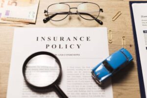 Insurance Policy document with toy car, magnify glass and goggle